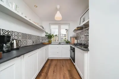 a kitchen with white cabinets and black counter tops at Close to everywhere, cosy place in Kraków