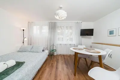 a white bedroom with a bed and a table at Close to everywhere, cosy place in Kraków