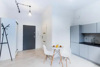a kitchen with white cabinets and a table and chairs at Apartment Quiet Street 11/5E in Oświęcim