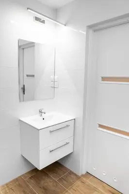 a white bathroom with a sink and a mirror at Apartment Quiet Street 11/5E in Oświęcim
