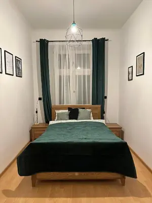 a bedroom with a large bed with a green blanket at Wielopole Classy Rooms in Kraków