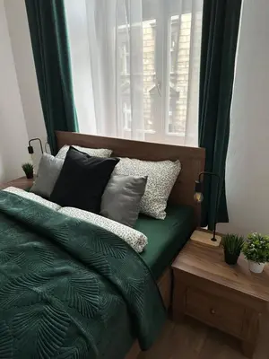 a bedroom with a bed with green sheets and pillows at Wielopole Classy Rooms in Kraków