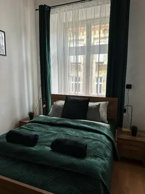 a bedroom with a green bed with a window at Wielopole Classy Rooms in Kraków