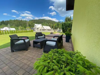 a patio with four chairs and a table and a green wall at Apartamenty i pokoje w Zawoi Dorota Miśkowiec in Zawoja