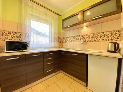 a kitchen with brown cabinets and a microwave at Apartamenty i pokoje w Zawoi Dorota Miśkowiec in Zawoja