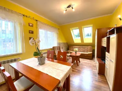 a living room with yellow walls and a dining table at Apartamenty i pokoje w Zawoi Dorota Miśkowiec in Zawoja