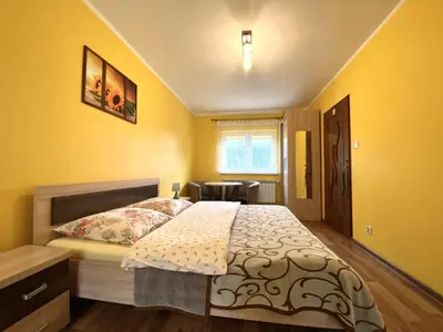 a bedroom with a bed with yellow walls and a window at Apartamenty i pokoje w Zawoi Dorota Miśkowiec in Zawoja