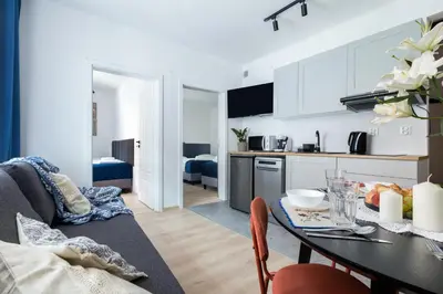 a kitchen and living room with a table and chairs at Józefa 12 Apartments in Kraków