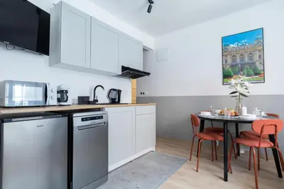 a kitchen with white cabinets and a table with chairs at Józefa 12 Apartments in Kraków