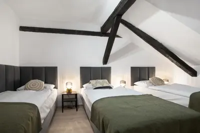 two beds in a room with white walls and wooden beams at Józefa 12 Apartments in Kraków