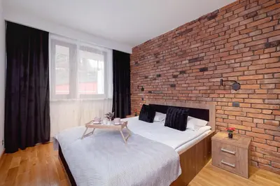 a bedroom with a brick wall and two beds at Industrial Apartment Fredry with Parking by Noclegi Renters in Kraków