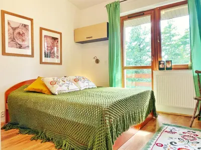 a bedroom with a bed with a green comforter and a window at Luxury, spacious apartament with two bedrooms and balcony in Przybysławice