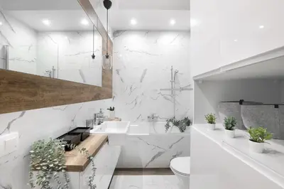 a bathroom with white marble walls and a sink at Classy 2-room Apartment with Private Garden and Air Conditioning- Old Town in Kraków