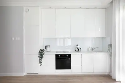 a kitchen with white cabinets and a black dishwasher at Classy 2-room Apartment with Private Garden and Air Conditioning- Old Town in Kraków