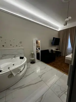 a white bathroom with a tub and a living room at Jacuzzi Berka Apartamenty in Kraków