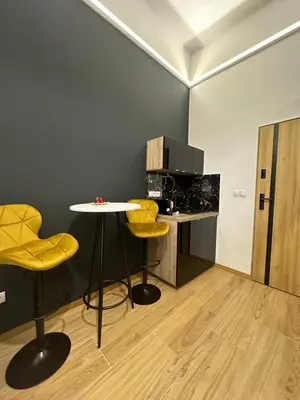 a kitchen with a table and two yellow stools at Jacuzzi Berka Apartamenty in Kraków