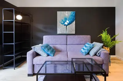 a purple couch with blue pillows in a living room at Modern apt next to train station in Kraków