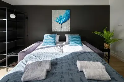 a bedroom with a large bed with blue pillows at Modern apt next to train station in Kraków