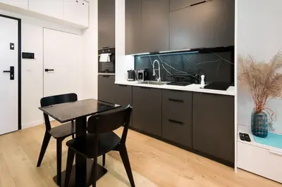 a kitchen with a table and a black chair in it at Modern apt next to train station in Kraków