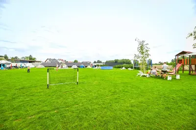 a group of people sitting on a grass field with a goal at KempingZator Glamping in Zator