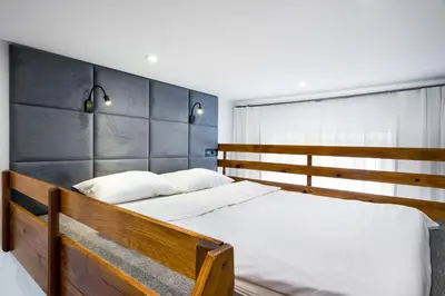 a bedroom with a wooden bed with white sheets at Apartament Felicjanek in Kraków