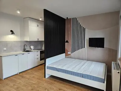 a small bedroom with a bed and a kitchen at Apartamenty Orawska 14 in Kraków