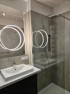 a bathroom with a sink and a glass shower at Apartamenty Orawska 14 in Kraków
