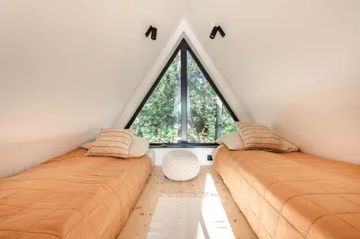 two beds in a room with a large window at Budzi nas las Marcyporęba - Duży domek in Marcyporęba