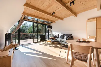 an open living room with a table and chairs at Budzi nas las Marcyporęba - Duży domek in Marcyporęba