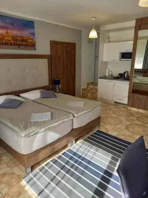 a bedroom with a large bed and a kitchen at Mini Apartamenty Centrum in Kraków