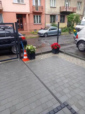 a parking lot with a fence and some plants at Mini Apartamenty Kraków in Kraków