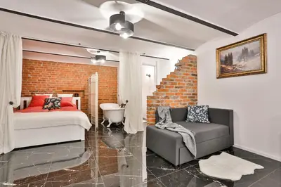 a bedroom with a bed and a chair and a brick wall at Apartament Zielona Willa in Skomielna Biała