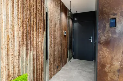 a hallway with a wooden wall and a black door at Wiślane Tarasy - UNIQUE Apartments 4YOU - 10 piętro z pięknym widokiem na centrum Krakowa in Kraków