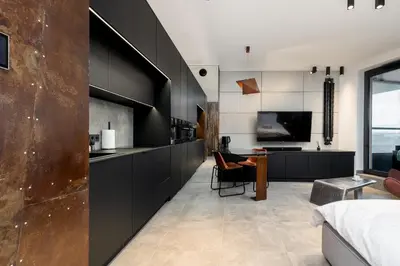 a bedroom with black cabinets and a living room at Wiślane Tarasy - UNIQUE Apartments 4YOU - 10 piętro z pięknym widokiem na centrum Krakowa in Kraków