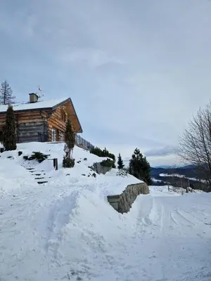 a log cabin in the snow next to a road at Chata Palarówka in Grzechynia