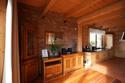 a kitchen with wooden cabinets and a brick wall at Chata Palarówka in Grzechynia
