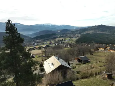 a small house in a field with mountains in the background at Chata Palarówka in Grzechynia