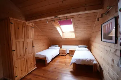 two beds in a wooden room with a window at Chata Palarówka in Grzechynia