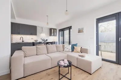 a white living room with a white couch and a kitchen at Apartment in Krakow with parking and balcony by Noclegi Renters in Modlnica