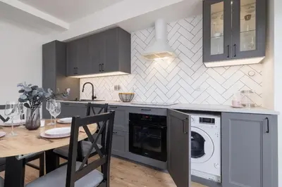 a kitchen with a washer and dryer and a table at Apartment in Krakow with parking and balcony by Noclegi Renters in Modlnica