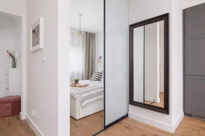 a mirror in a white room with a bed at Apartment in Krakow with parking and balcony by Noclegi Renters in Modlnica