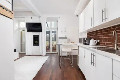 a kitchen with white cabinets and a brick wall at Lux Studio City Center Sołtyka by Noclegi Renters in Kraków