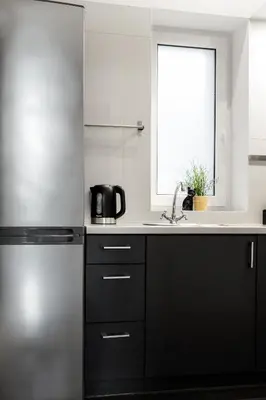 a kitchen with black and white appliances and a window at Househost Apartment: Józefa 2/10 in Kraków