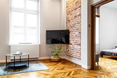 a living room with a tv and a brick wall at Househost Apartment: Józefa 2/10 in Kraków