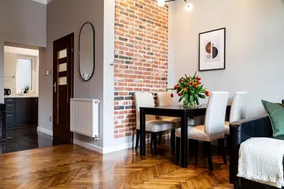 a dining room with a table and a brick wall at Househost Apartment: Józefa 2/10 in Kraków