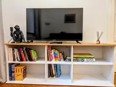 a tv on top of a book shelf with books at Paulińska 18 by Homeprime in Kraków