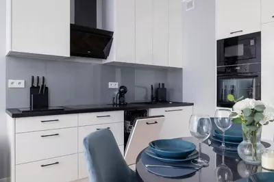 a kitchen with white cabinets and a glass table with blue dishes at Unique Apartment with Balcony & Parking Zabłocie Cracow by Renters Prestige in Kraków