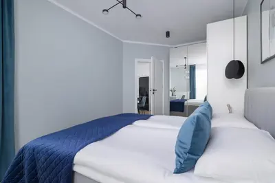 a bedroom with a white bed with blue pillows at Unique Apartment with Balcony & Parking Zabłocie Cracow by Renters Prestige in Kraków