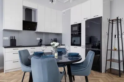 a kitchen with a table and chairs and a kitchen with white cabinets at Unique Apartment with Balcony & Parking Zabłocie Cracow by Renters Prestige in Kraków