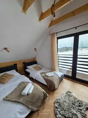 two beds in a room with a large window at Okno Na Góry in Klikuszowa